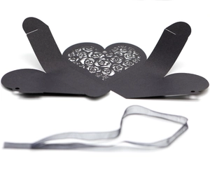 Detail view of heart-shaped hollow rose patterns on a black cardstock gift box with ribbon