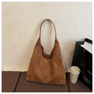 Detailed view of brown suede hobo bag with sleek handle in a lifestyle shopping setting
