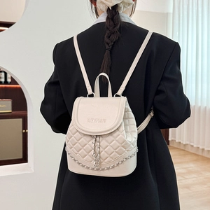 Close-up of cream quilted mini backpack with WOMAN embroidery and silver chain detail