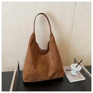 Detail view of the brown faux suede hobo tote bag featuring a smooth leather shoulder strap