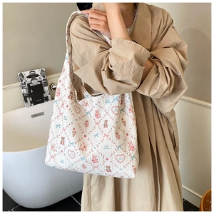 Close-up of quilted tote bag with cute cartoon bear prints held by a model in a trench coat