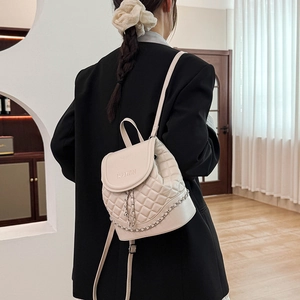 Detail view of cream quilted backpack with WOMAN embossed logo and chain straps