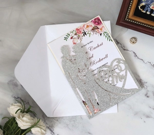 Macro detail of laser-cut wedding invitation with glitter finish and floral inner page