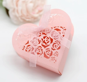 Macro shot of laser-cut rose patterns on a pink wedding favor box with ribbon
