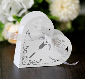 Detail of laser-cut hollow floral pattern and white ribbon on heart-shaped gift box