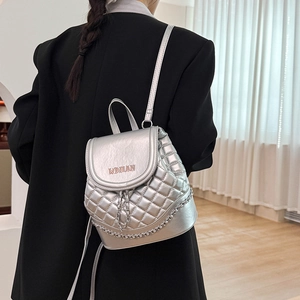 Detailed close-up of quilted silver bucket backpack with metal chain and WOMAN text