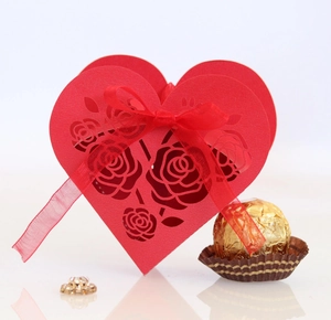 Detail of red heart-shaped laser-cut gift box with rose pattern and red ribbon bow
