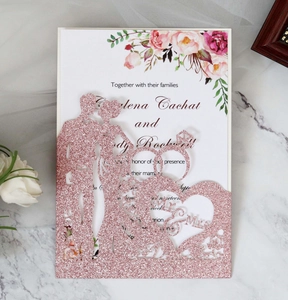 Detail of pink glitter laser-cut wedding invitation with hollow Mr & Mrs heart pattern