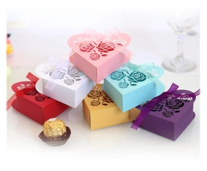 Hollow heart wedding candy boxes with laser-cut rose patterns and organza ribbons