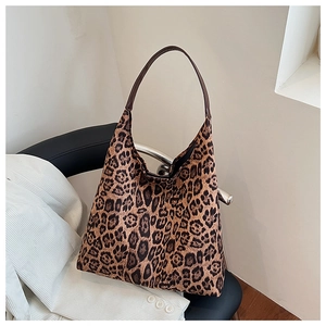 Close-up of leopard print tote bag with brown leather handle on a minimalist chair