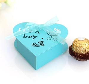 Detail view of light blue heart-shaped baby boy favor box with silk ribbon and It's a boy text