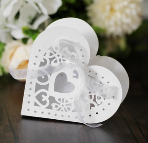 Gros plan sur une boîte cadeau cœur blanche découpée au laser avec motif floral et ruban