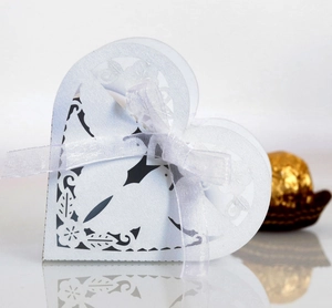 Detail of laser-cut white heart candy box with elegant floral patterns and ribbon