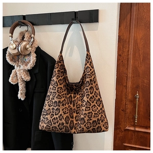 Detail of leopard print tote bag with brown leather straps hanging in a fashion scene