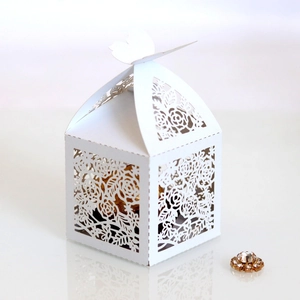 Detail of laser-cut ivory butterfly wedding favor box with intricate rose patterns