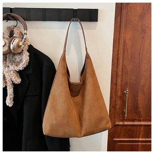 Brown suede Hobo tote bag hanging on a hook next to a blazer and headphones