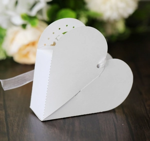 Détail de la boîte à dragées blanche en forme de cœur avec ruban et motifs découpés