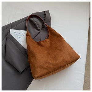 Detail of a large brown suede hobo tote bag featuring dark brown leather straps and texture