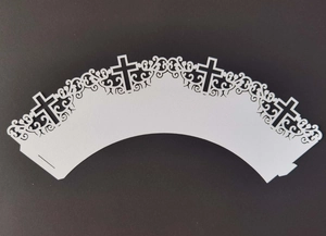 Detailed laser-cut white cupcake wrapper with cross patterns and vine decorations