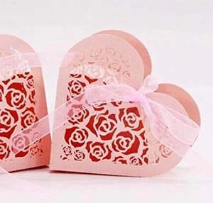 Detail view of heart-shaped pink favor box with laser-cut roses and elegant ribbon