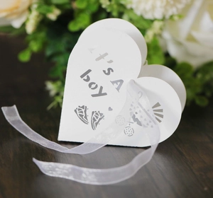 White heart-shaped favor box with laser-cut It's a Boy text and baby stroller detail