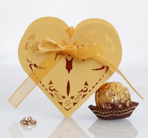 Detail showing golden laser-cut heart candy box with intricate floral hollow pattern
