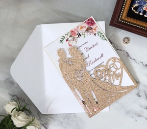Detailed close-up of gold glitter laser-cut wedding invitation with Mr & Mrs heart silhouette