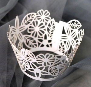 Elegant laser cut white paper cupcake wrapper with floral and leaf patterns for weddings