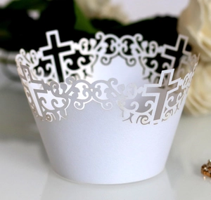 Intricate white laser-cut cupcake wrappers with cross design and floral lace patterns