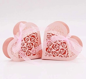 Detail of pink laser-cut heart favor box with rose patterns and a matching ribbon bow