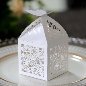 Detail of ivory laser-cut wedding favor box with rose patterns and butterfly closure