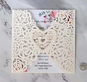 Macro view of laser-cut rose and heart patterns on pearlescent wedding invitations