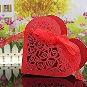 Detail of red heart-shaped laser-cut wedding favor box with intricate rose patterns