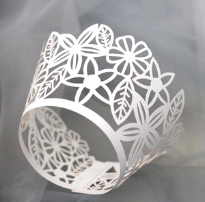 Close-up of laser-cut white flower and leaf patterns on decorative cupcake wrapper