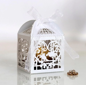 Macro detail of laser-cut wedding candy box with birdcage pattern and white ribbon