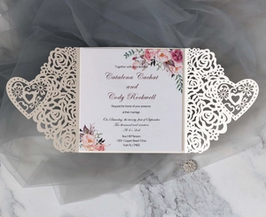 Detail view of laser-cut rose and heart hollow patterns on ivory wedding invitation card