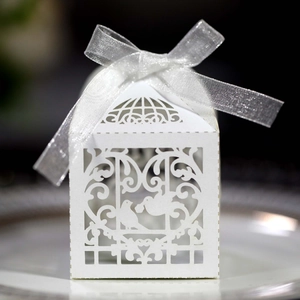 Close-up of laser-cut white favor box with bird heart patterns and silver ribbon