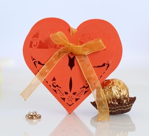 Detailed laser-cut heart favor box with elegant floral patterns and a golden satin bow