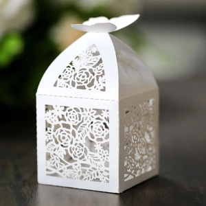Ivory laser cut butterfly wedding favor box with elegant rose patterns on wood surface