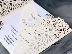 Detailed macro view of laser-cut rose and heart patterns on wedding invitations