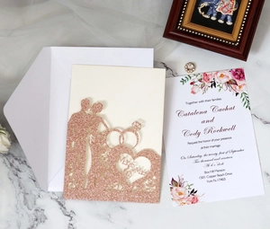 Detail of rose gold glitter laser-cut wedding invitation with hollow heart and floral insert