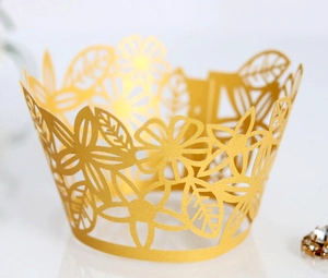 Macro detail of laser-cut gold floral cupcake wrapper for wedding and party decoration