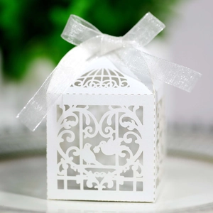 Close-up of laser-cut wedding favor box with love bird pattern and white organza ribbon