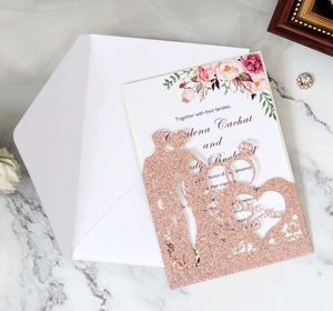 Close-up of laser-cut rose gold glitter wedding invitation with Mr & Mrs silhouette design
