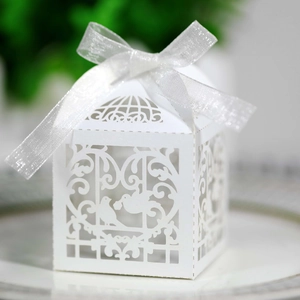 Laser-cut white wedding favor box with intricate bird motifs and white ribbon bow