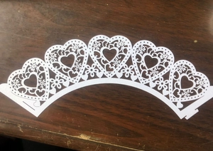 White laser cut heart and floral cupcake wrappers on vintage brown wooden background