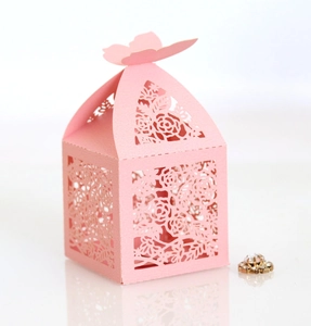 Close-up of pink laser-cut favor box with rose patterns and 3D butterfly closure