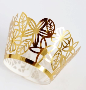Close-up of laser-cut cupcake wrapper featuring golden metallic floral and leaf patterns