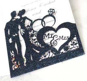Close-up of Mr & Mrs black glitter wedding topper with rings and couple silhouette