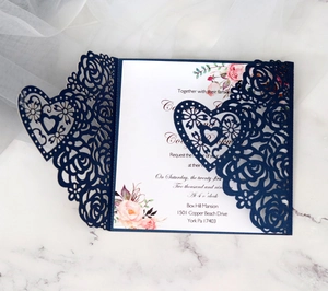 Detail of laser-cut rose and heart patterns on deep blue wedding invitation cards